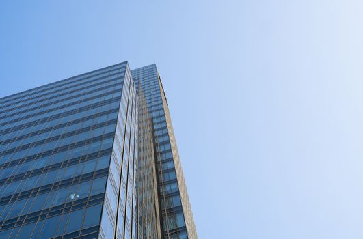 Reflection of the sky in the windows of a building. Perspective and underdite angle view to modern glass building skyscrapers over blue sky. Windows of Bussiness office or corporate building