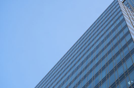 Reflection of the sky in the windows of a building. Perspective and underdite angle view to modern glass building skyscrapers over blue sky. Windows of Bussiness office or corporate building