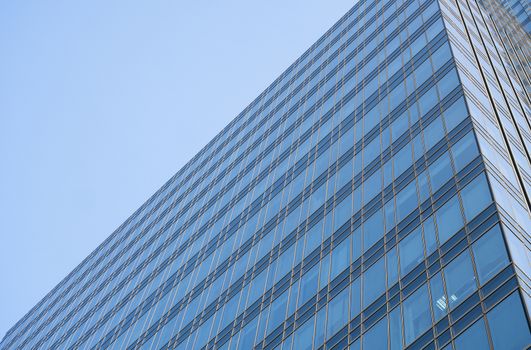 Reflection of the sky in the windows of a building. Perspective and underdite angle view to modern glass building skyscrapers over blue sky. Windows of Bussiness office or corporate building