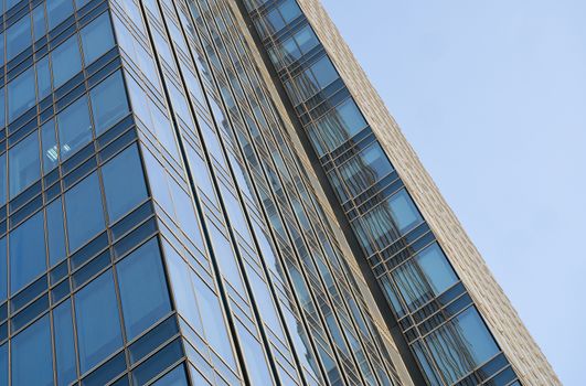 Reflection of the sky in the windows of a building. Perspective and underdite angle view to modern glass building skyscrapers over blue sky. Windows of Bussiness office or corporate building