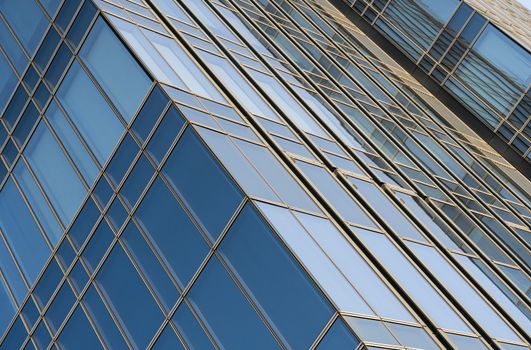 Reflection of the sky in the windows of a building. Perspective and underdite angle view to modern glass building skyscrapers over blue sky. Windows of Bussiness office or corporate building