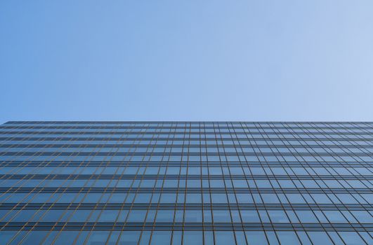 Reflection of the sky in the windows of a building. Perspective and underdite angle view to modern glass building skyscrapers over blue sky. Windows of Bussiness office or corporate building