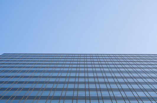 Reflection of the sky in the windows of a building. Perspective and underdite angle view to modern glass building skyscrapers over blue sky. Windows of Bussiness office or corporate building