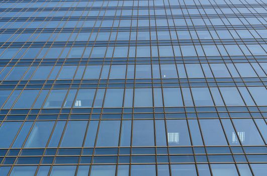 Reflection of the sky in the windows of a building. Perspective and underdite angle view to modern glass building skyscrapers over blue sky. Windows of Bussiness office or corporate building