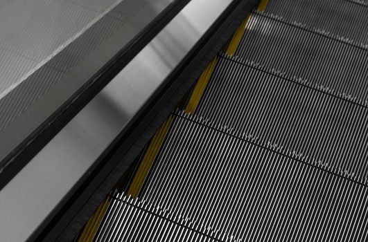 Modern escalator electronic system moving. Escalator is moving up.The ground is a straight line. Black with yellow band