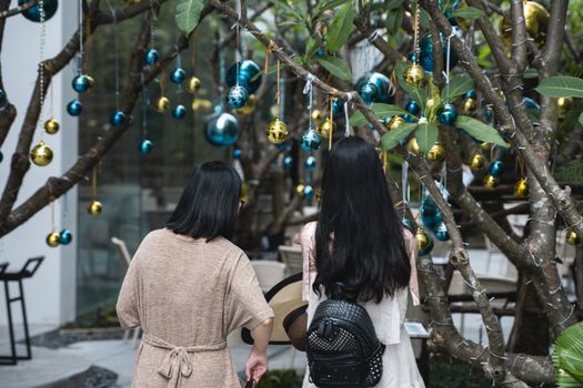 Two girls is standing near decorated Christmas tree with a blue and gold toys and beautiful blue butterfly toy. Holidays. Preparation for New Year and Christmas