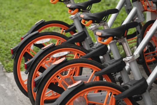 Street transportation orange hybrid rent bicycles with electronic form of payment for traveling around the city stand in row