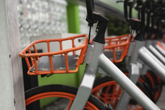 Street transportation orange hybrid rent bicycles with electronic form of payment for traveling around the city stand in row