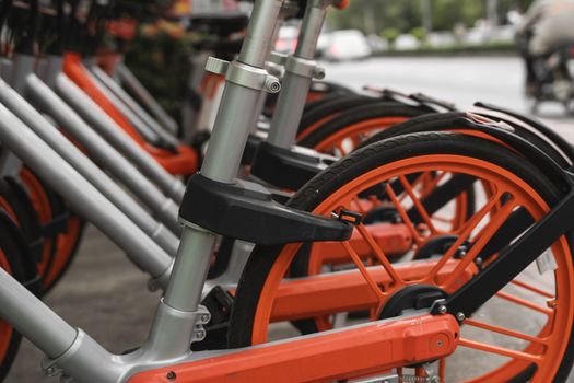 Street transportation orange hybrid rent bicycles with electronic form of payment for traveling around the city stand in row