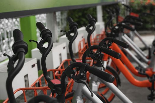 Street transportation orange hybrid rent bicycles with electronic form of payment for traveling around the city stand in row