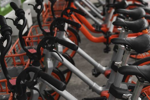 Street transportation orange hybrid rent bicycles with electronic form of payment for traveling around the city stand in row