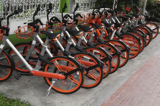 Street transportation orange hybrid rent bicycles with electronic form of payment for traveling around the city stand in row