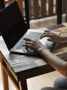 Woman's hands typing on laptop keyboard. Study and work online, freelance. Self employed or freelance woman, girl working with her laptop sitting at wooden table with a phone, smartphone and ereader
