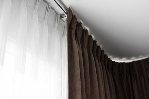 Brown curtains on a rail with a white ceiling. Curtain interior decoration in living or sleeping room. Comfortable live in your own home. Sweet confy home