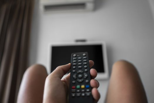 The man with the remote control in hand want switch on the TV and presses the button on the remote control. Remote control in hand closeup