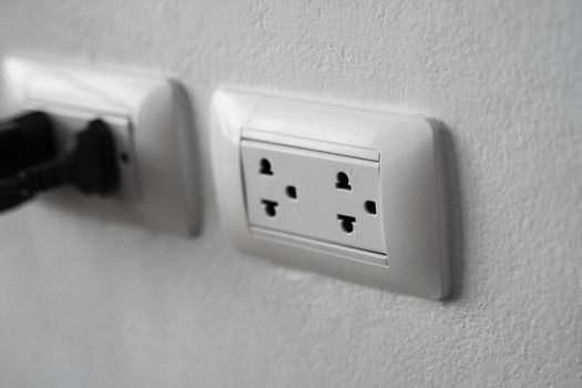 White universal electricity sockets plug on a white wall