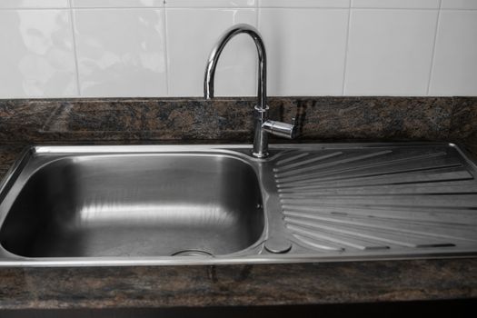 Close up on modern kitchen metal faucet and metal kitchen sink