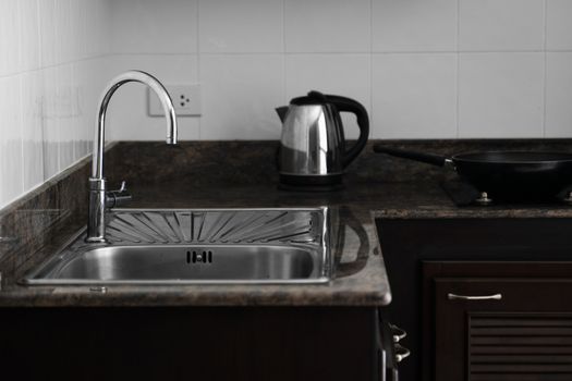 Close up on modern kitchen metal faucet and metal kitchen sink