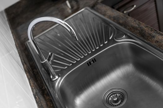 Close up on modern kitchen metal faucet and metal kitchen sink