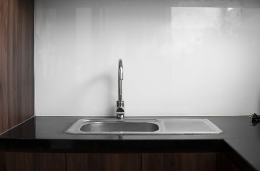Close up on modern kitchen metal faucet and metal kitchen sink