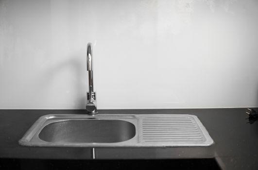 Close up on modern kitchen metal faucet and metal kitchen sink