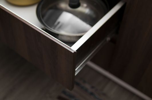 Metal chromed pots in a drawer in a modern kitchen