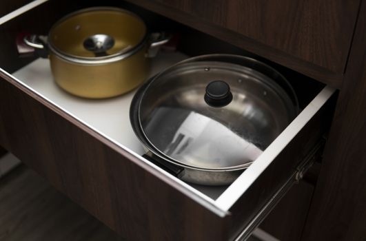 Metal chromed pots in a drawer in a modern kitchen