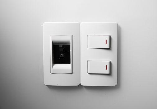 White switch on a white wall with two switches and one common switch