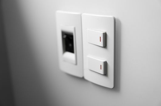 White switch on a white wall with two switches and one common switch