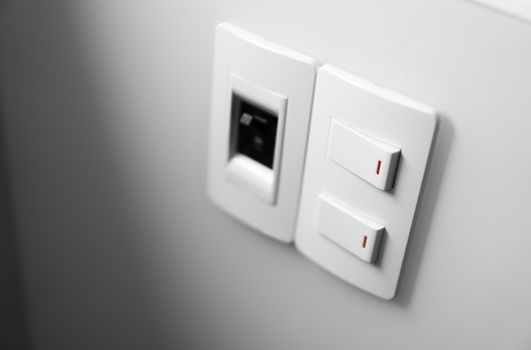 White switch on a white wall with two switches and one common switch