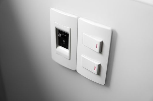 White switch on a white wall with two switches and one common switch