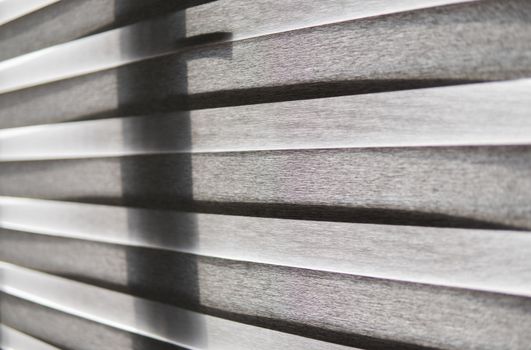 Details of brown fabric roller blinds on the plastic window with wood texture in the living room