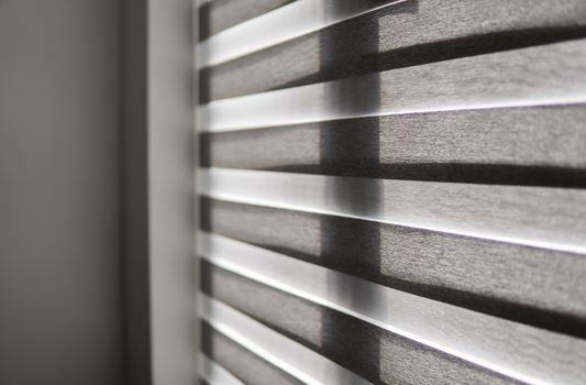 Details of brown fabric roller blinds on the plastic window with wood texture in the living room