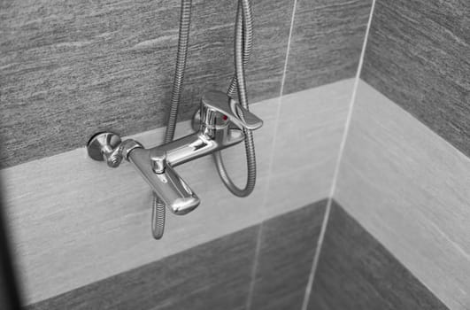 Modern designer tap and shower in bathroom. Closeup of chrome shower, faucet, in the bathroom covered decorative ceramic. Mixer cold hot water