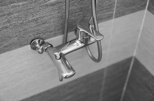 Modern designer tap and shower in bathroom. Closeup of chrome shower, faucet, in the bathroom covered decorative ceramic. Mixer cold hot water