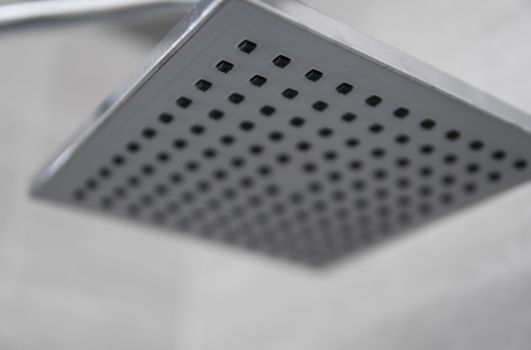 Square shower head in a modern bathroom. Shower in the bathroom with water spray or water. Feel relaxed and enjoy in the bathroom. A stream of fresh water from the shower head to clean the dirty body