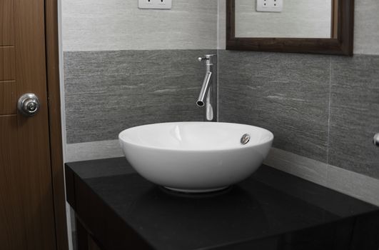 Bathroom interior with white round sink and chrome faucet in a modern bathroom