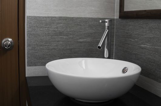 Bathroom interior with white round sink and chrome faucet in a modern bathroom