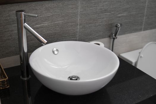 Bathroom interior with white round sink and chrome faucet in a modern bathroom