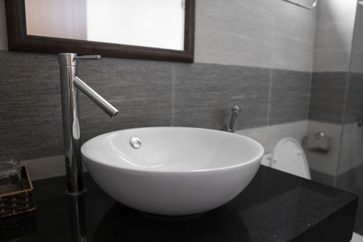 Bathroom interior with white round sink and chrome faucet in a modern bathroom