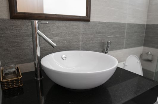 Bathroom interior with white round sink and chrome faucet in a modern bathroom