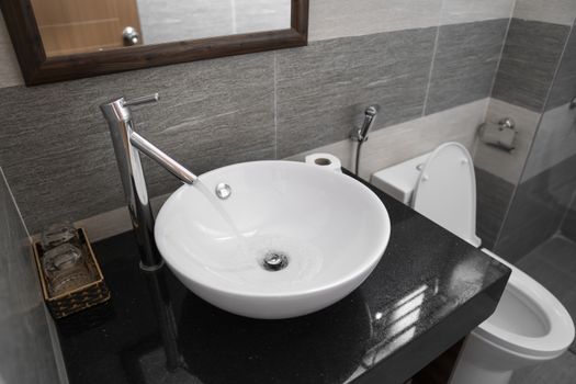 Bathroom interior with white round sink and chrome faucet in a modern bathroom