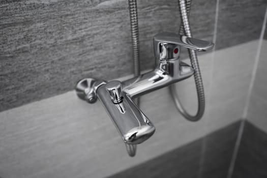 Modern designer tap and shower in bathroom. Closeup of chrome shower, faucet, in the bathroom covered decorative ceramic. Mixer cold hot water