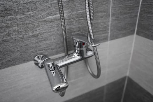 Modern designer tap and shower in bathroom. Closeup of chrome shower, faucet, in the bathroom covered decorative ceramic. Mixer cold hot water