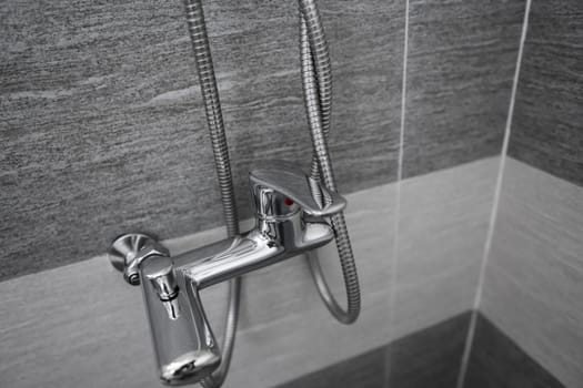 Modern designer tap and shower in bathroom. Closeup of chrome shower, faucet, in the bathroom covered decorative ceramic. Mixer cold hot water