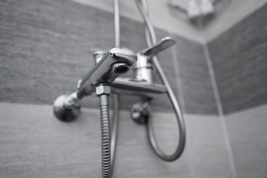Modern designer tap and shower in bathroom. Closeup of chrome shower, faucet, in the bathroom covered decorative ceramic. Mixer cold hot water