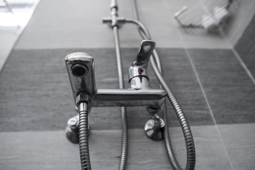 Modern designer tap and shower in bathroom. Closeup of chrome shower, faucet, in the bathroom covered decorative ceramic. Mixer cold hot water
