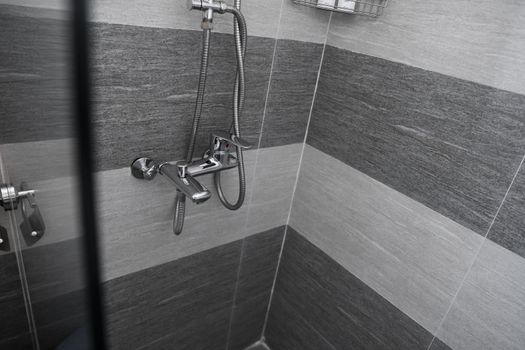 Modern designer tap and shower in bathroom. Closeup of chrome shower, faucet, in the bathroom covered decorative ceramic. Mixer cold hot water