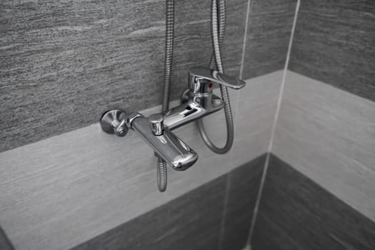 Modern designer tap and shower in bathroom. Closeup of chrome shower, faucet, in the bathroom covered decorative ceramic. Mixer cold hot water