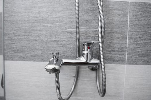 Modern designer tap and shower in bathroom. Closeup of chrome shower, faucet, in the bathroom covered decorative ceramic. Mixer cold hot water